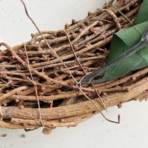 Weave floral wire through wreath and eucalyptus stems
