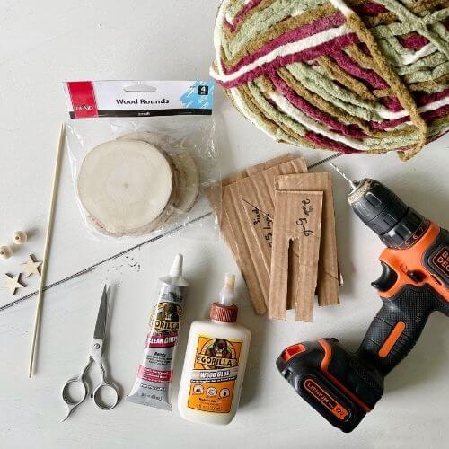 Supplies including yarn, wood slices, skewers, cardboard, wood beads, a drill and glue