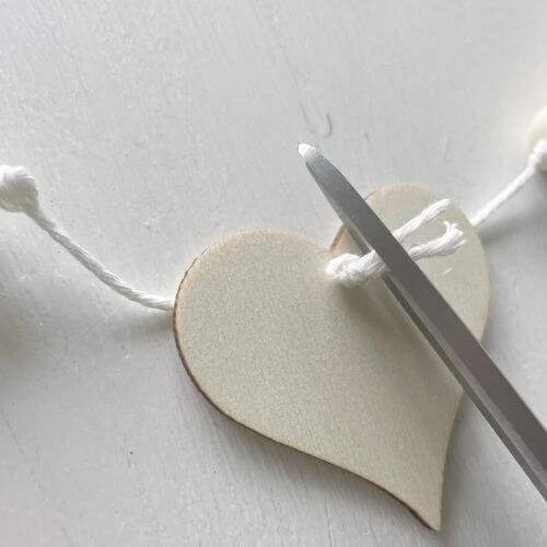 Cut excess string from wood heart knot