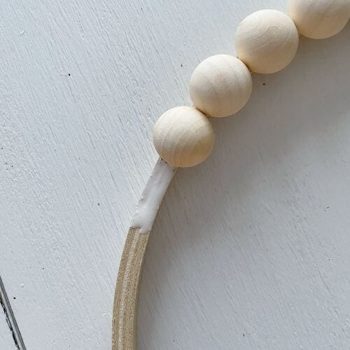 Glue half wood beads to embroidery hoop