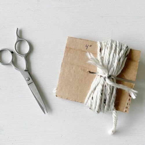 Create yarn flower by wrapping yarn around cardboard and tying