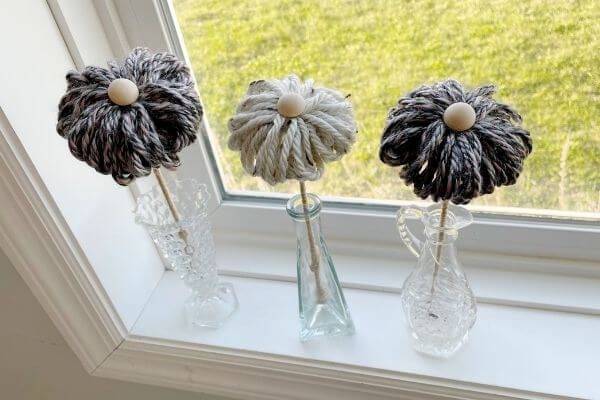 3 yarn flowers displayed on windowsill