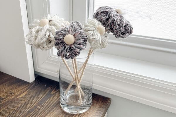 3 cozy yarn flowers displayed on windowsill