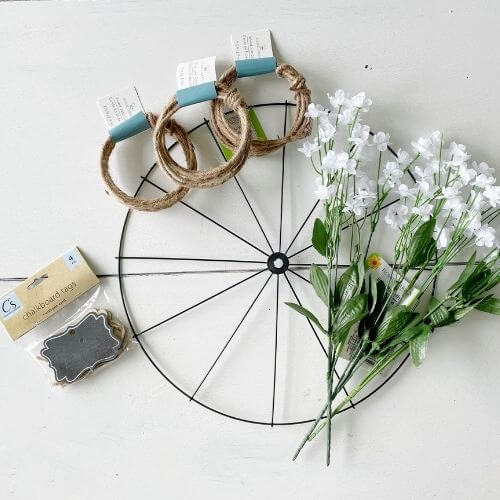 Bike wheel form, jute twine, floral, and chalkboard tags