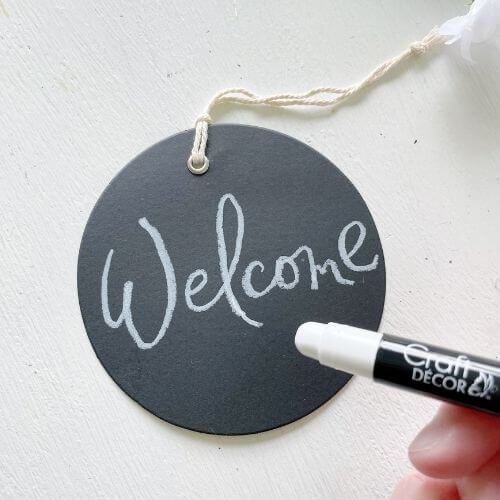 Write "welcome" on your chalkboard tag with marker