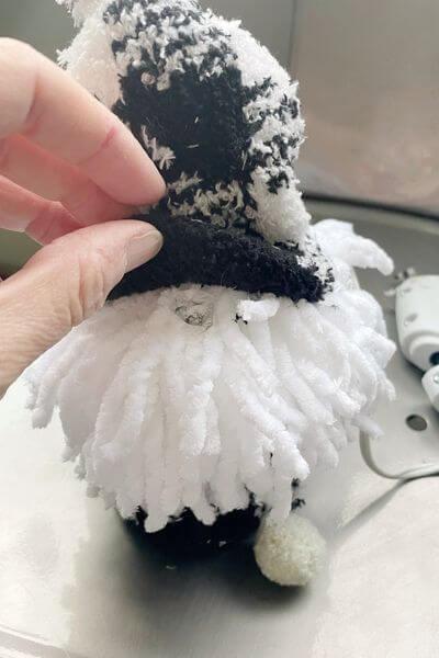 Place dab of glue under front of hat and secure nose pom-pom