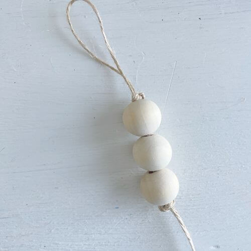 Place three 20 mm wood beads on string and secure with double knots