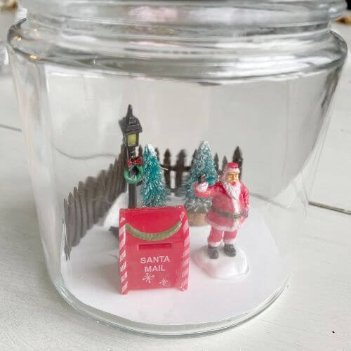 Figurines glued to cardstock inside glass jar