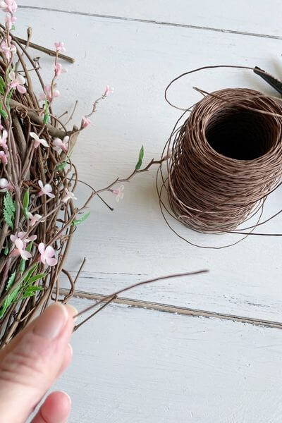 Cut 2-3 inches of brown floral wire to secure pink floral stem to wreath