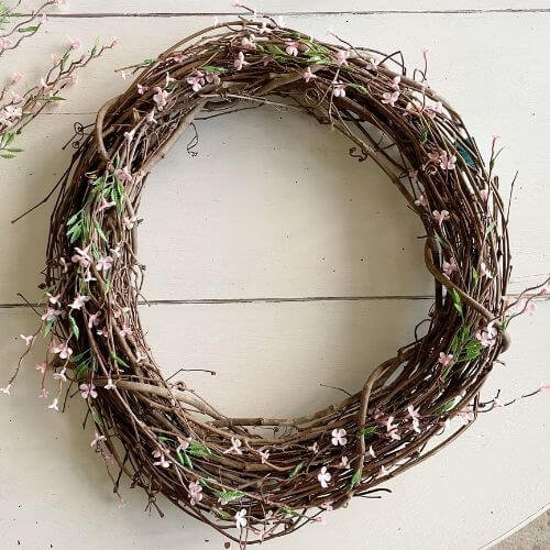 One pink floral stem woven into grapevine wreath.