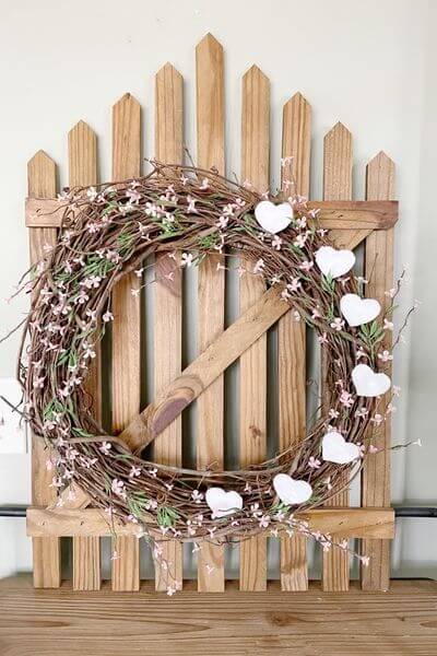 Finished grapevine Valentine wreath hung on decorative fence.