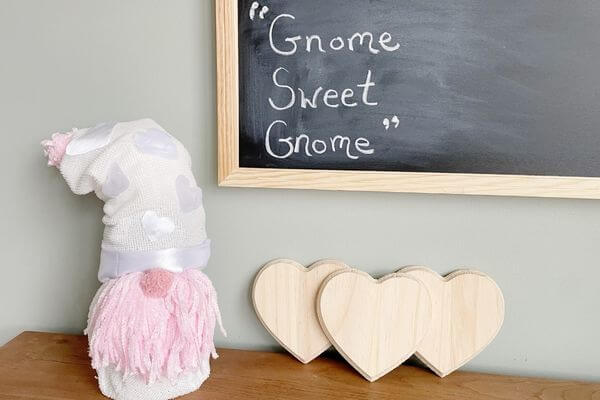Valentine Gnome next to 3 wood hearts and a chalkboard that states "Gnome Sweet Gnome"