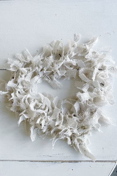 Heart wreath form covered in white burlap.