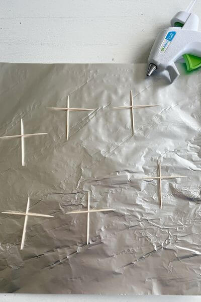 Toothpicks placed in a cross pattern on tin foil