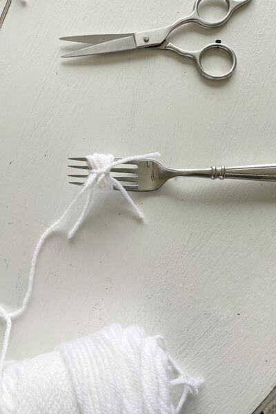 Yarn wrapped around fork and tied in the middle with another piece of yarn.