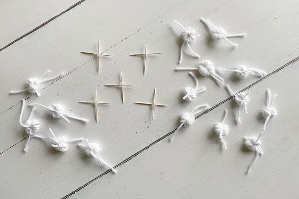 Five toothpick crosses and fifteen yarn pom poms.