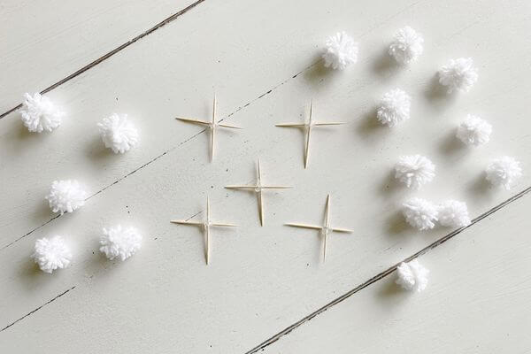 Picture of five toothpick crosses and fifteen pom poms.