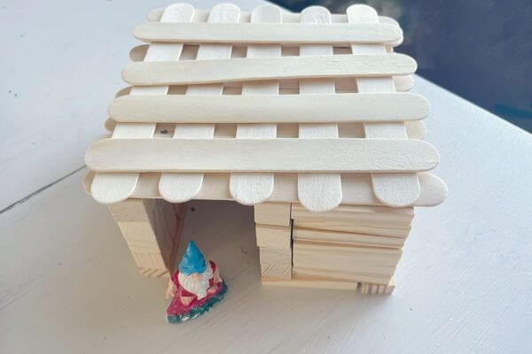 Gnome house built without glue with gnome figurine in doorway.