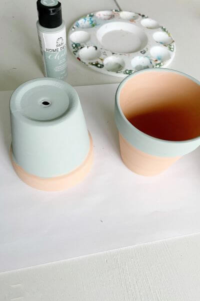 Two terra cotta pots that are painted sage green.