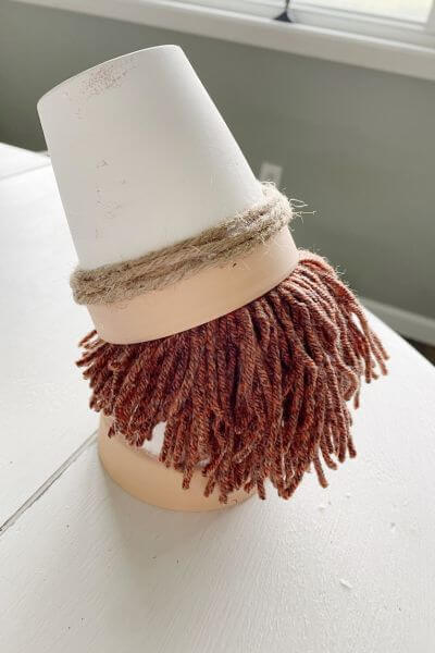 First do a trial by placing the yarn beard on top of the flowerpot and then putting the gnome hat on top.