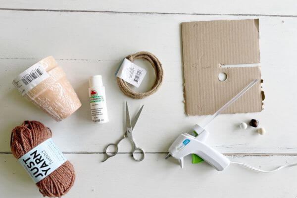 Supplies including clay pots, yarn, paint, jute wire, scissors, cardboard, beads and glue gun.