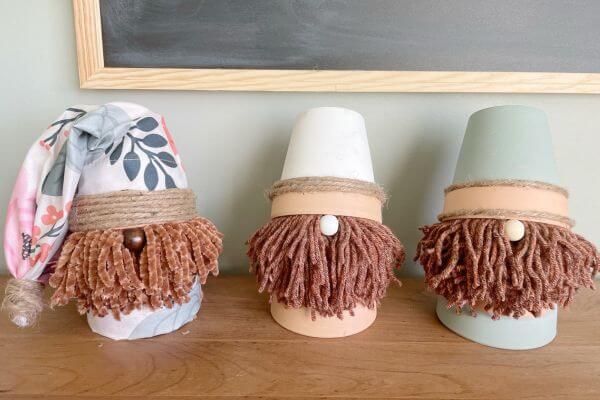 Three terra cotta pot gnomes made with a yarn beard. 