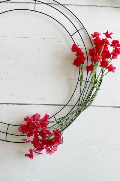 Two red Baby's Breath stems positioned on the wreath form.