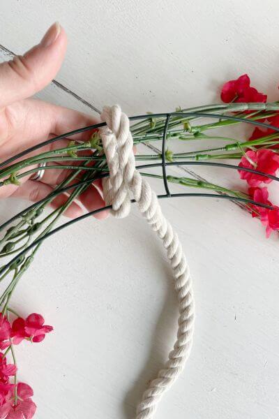 Hot glue the rope at the back of the wreath and then begin wrapping it around the wreath form.