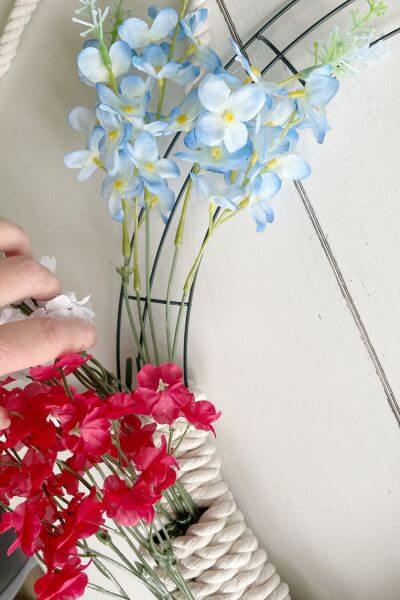 Tuck the blue Larkspur floral stem into your wreath.