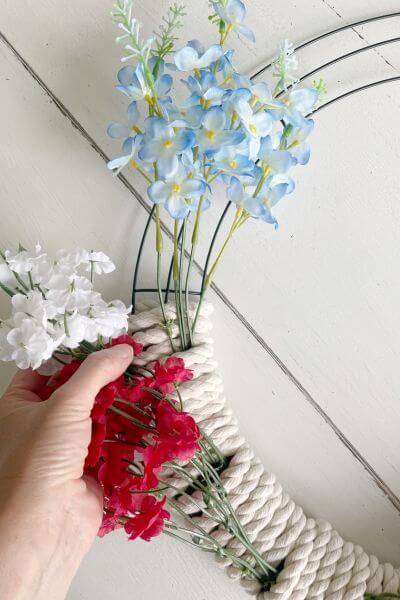 Continue wrapping your rope around the wreath form and underneath the blue flower stems. 