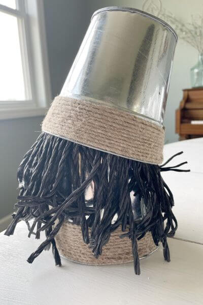 Push the second galvanized vase hat onto the gnome beard tilting it a little. 