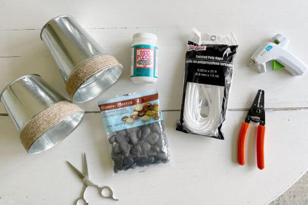 Supplies including galvanized vases, mod podge, scissors, rocks, rope, wire cutters and glue gun.