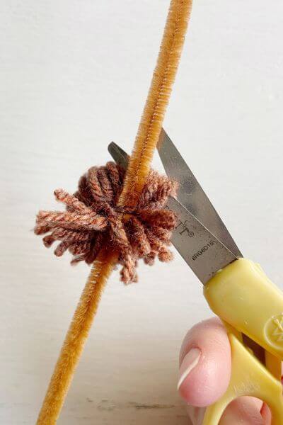 Continue cutting around the yarn ball to create the pom-pom.