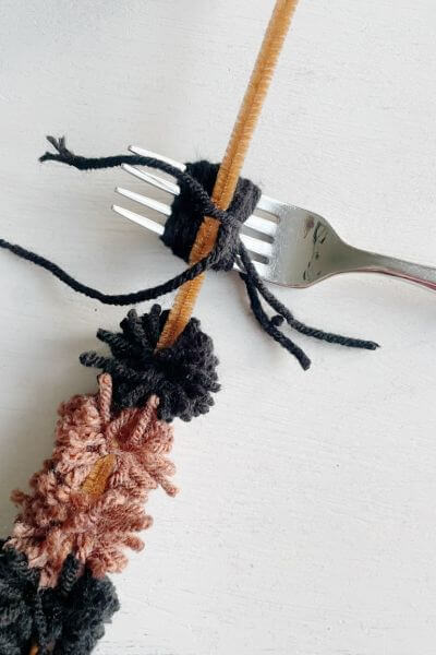 Add one more black pom-pom to complete the caterpillar.