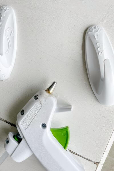 Glue gun with two white command hooks.