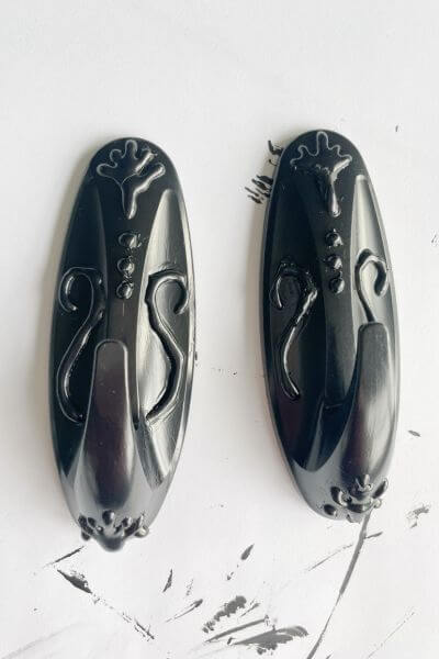 Two command hooks painted black using multi-surface paint.