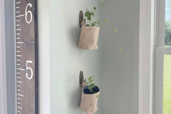 Two DIY vintage inspired command hooks holding plants in burlap wall baskets.