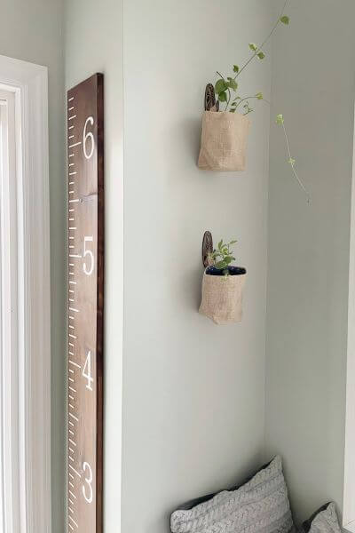 Two burlap wall planters hanging on a wall with DIY vintage inspired command hooks. 