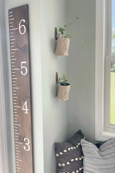 Two burlap hanging baskets on wall hung using DIY vintage looking command hooks. 