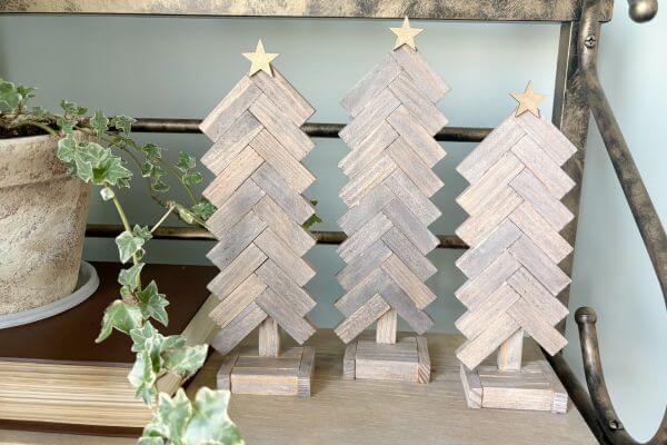Three trees standing on a shelf with gold stars on top. 