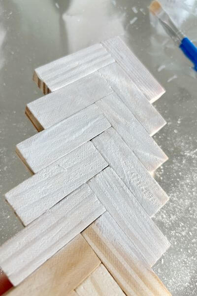 Apply the white paint wash in small sections to the Jenga block tree. 