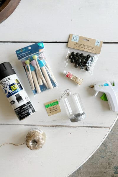 Supplies including spray paint, plastic ornament, jute twine, glue gun, Rub n' Buff, wood beads, and craft foam sticks.  