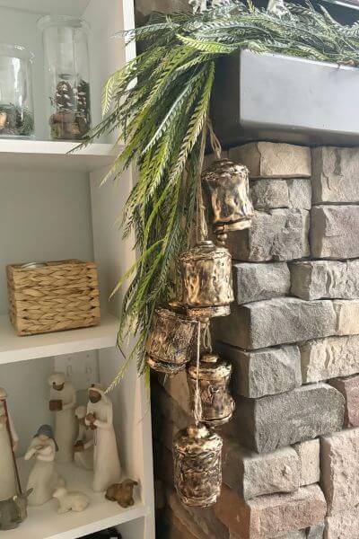 Five DIY bells hanging off a mantel on the side of the fireplace. 
