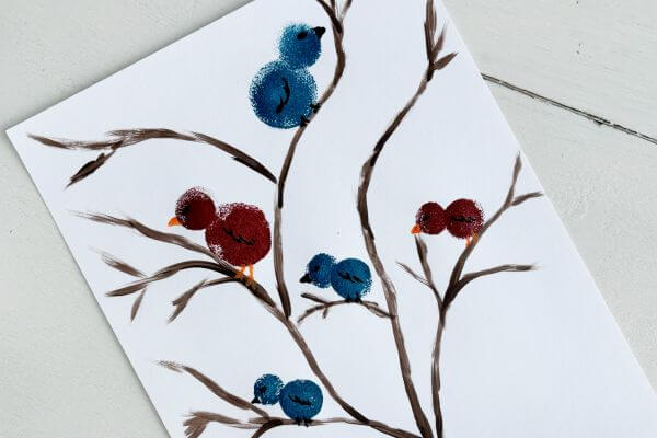 Five red and blue birds painted on a brown tree.