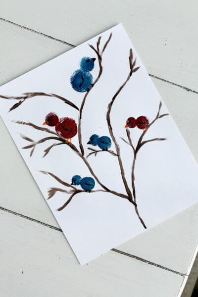 Five red and blue birds on a painted tree on cardstock paper. 
