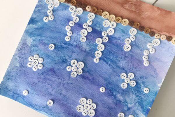 Watercolor and salt painting with buttons glued to it in the shape of icicles.