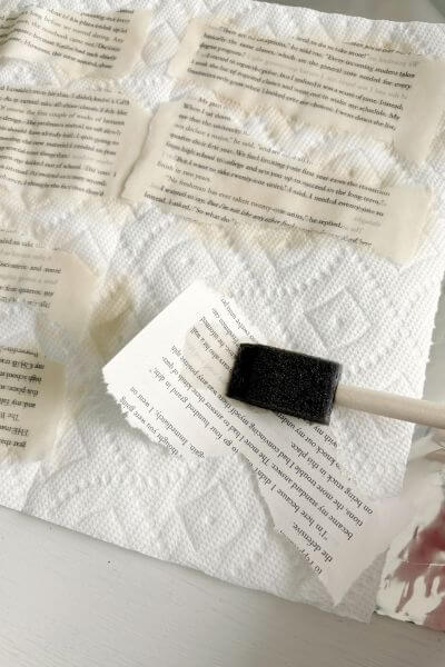 Craft sponge applying the tea to the torn book pages. 