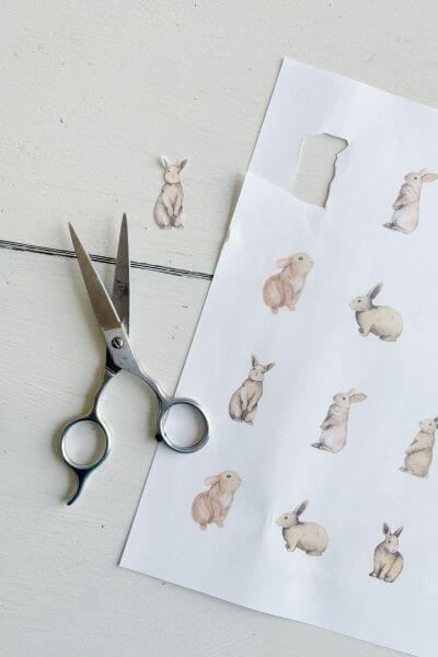 Free printable with one rabbit cut out, sitting next to a pair of scissors.