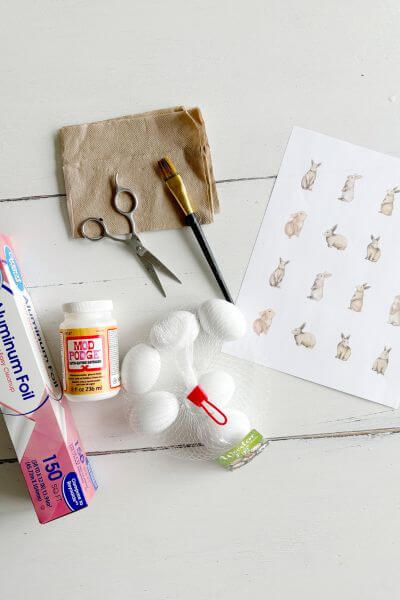 Supplies including napkins, mod podge, wooden eggs, tin foil, and free printable. 