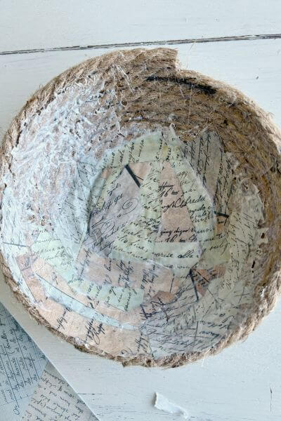Half the inside of bowl covered in torn paper pieces and sealed with mod podge.